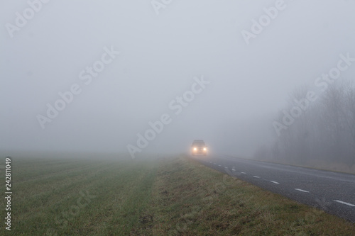 Car driving along a countryside road in heavy fog