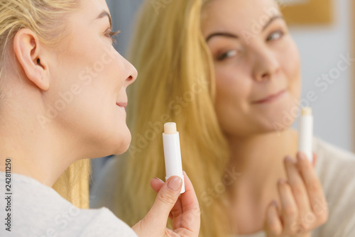 Woman in bathroom applying lip balm