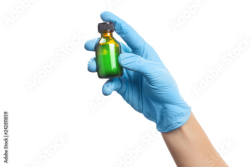 Hand in a blue rubber glove holding a bottle with unknown liquid of light green color, isolated on white background