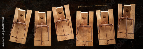Row of wooden mousetraps on black background
