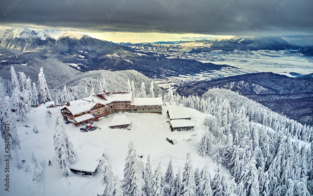 Aerial view over the spectacular ski slopes in the Carpathians mountains, Panoramic view over the ski slope Poiana Brasov ski resort in Transylvania,Romania,Europe,Pine forest covered in snow 
