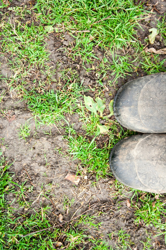 A man standing on the grass in galoshes. Visible shoes and grass in the fall.