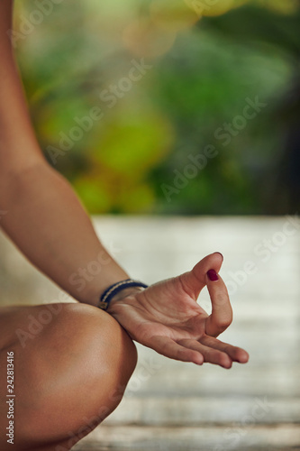 Young woman practicing yoga - meditation in the tropical garden. Focus on hand. © Kitja