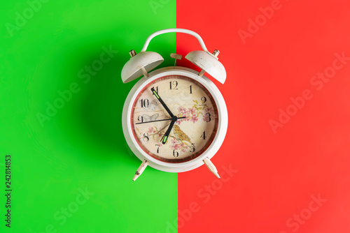 white retro alarm clock idolated on colorful background on wood surface b photo