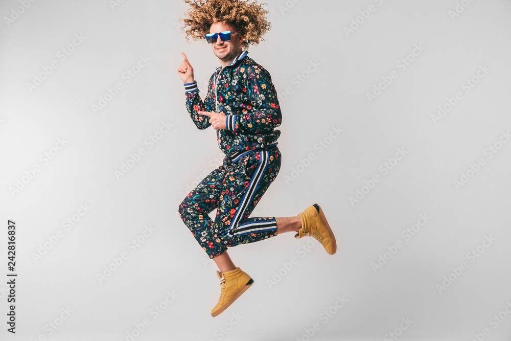 Adult positive smiling funky man with curly hair style in suglasses and  vintage clothes posing on white studio background. Funny portrait of  stylish male person. 80s fashion. Unusual eccentric guy. Stock Photo |