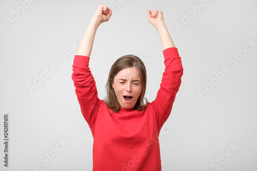 Happy young woman in red wear gesturing and keeping eyes closed