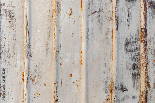 Background texture of rusty iron cladding on the exterior wall or roof of a building with peeling beige paint