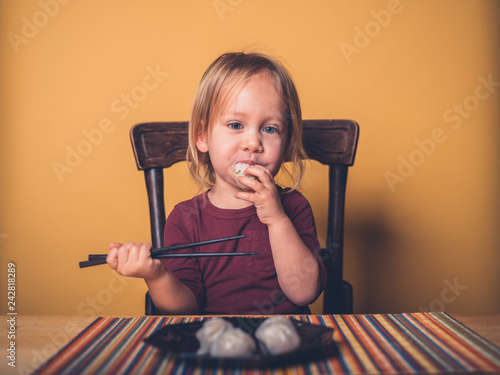 Little toddler eating dim sum with chop sticks
