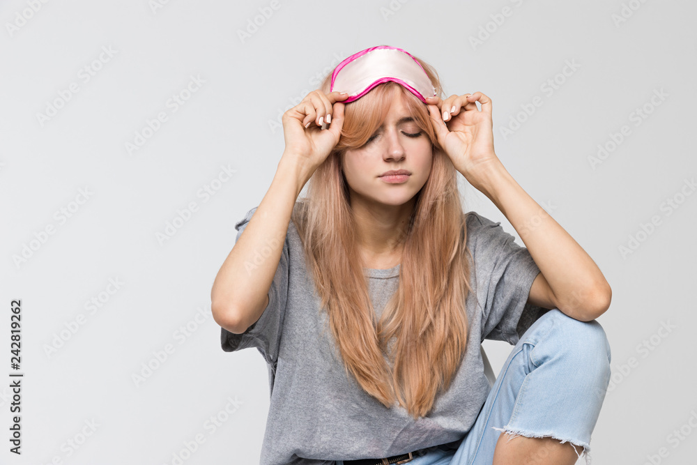 Close up studio portrait of young sleepy woman in grey t-shirt wearing a sleep mask/drowsiness, fatigue, lethargy, slackness, bored, tired, suffering from lack of sleep, early wakeup/ isolated. Close up studio portrait of young sleepy woman in grey t-shirt wearing a sleep mask/drowsiness, fatigue, lethargy, slackness, bored, tired, suffering from lack of sleep, early wakeup/ isolated.