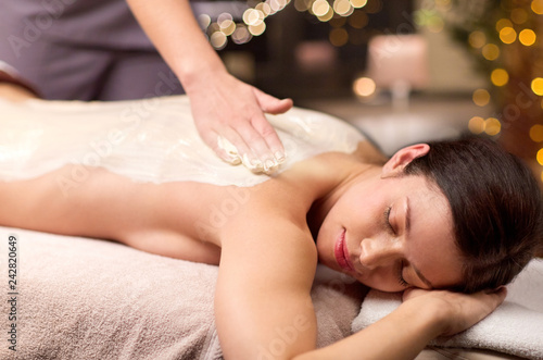 people, beauty, healthy lifestyle and relaxation concept - beautiful young woman lying and having back massage with cream at spa