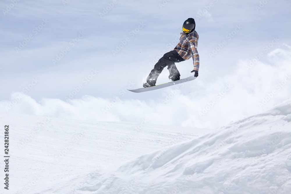 Snowboarder flying on the background of snowy slope. Extreme winter sports, snowboarding. Copy space.