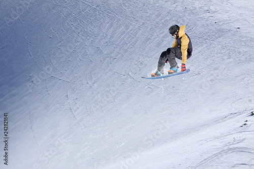 Snowboarder flying on the background of snowy slope. Extreme winter sports, snowboarding. Copy space.