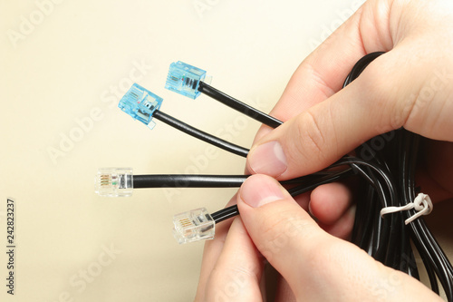Man holding black network cables with rj-45 connector on white