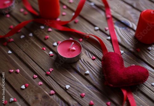 Red, pink felted hearts with red ribbon and candles on the wooden background