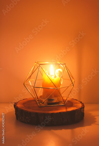 Hand made bee wax candle in a candleholder on wooden slice.
