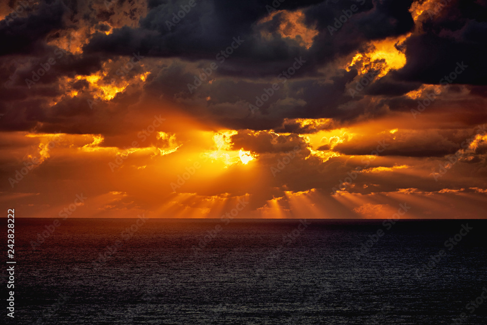 Obraz premium Dramatyczny zmierzch w morzu za ciemnymi ciężkimi chmurami