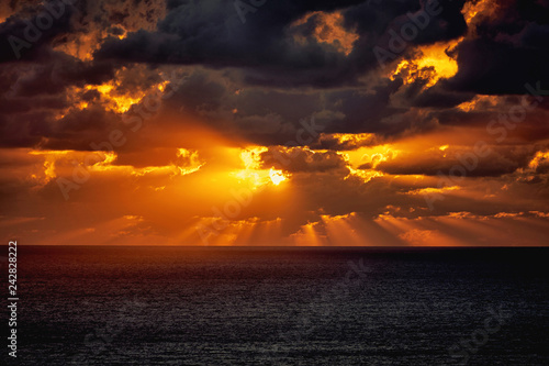Dramatic sunset in the sea behind the dark heavy clouds