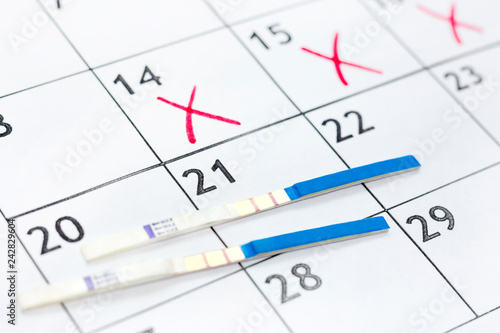 Two positive pregnancy test on calendar background. medical health care concept