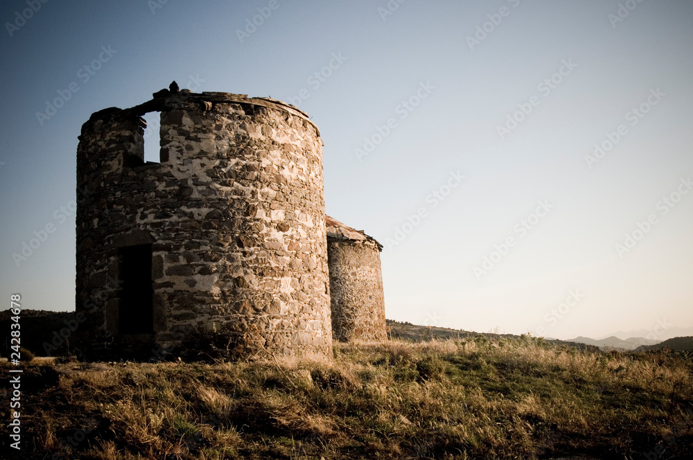 Some old ruins of ancient stone windmills on hill top in the sunset light