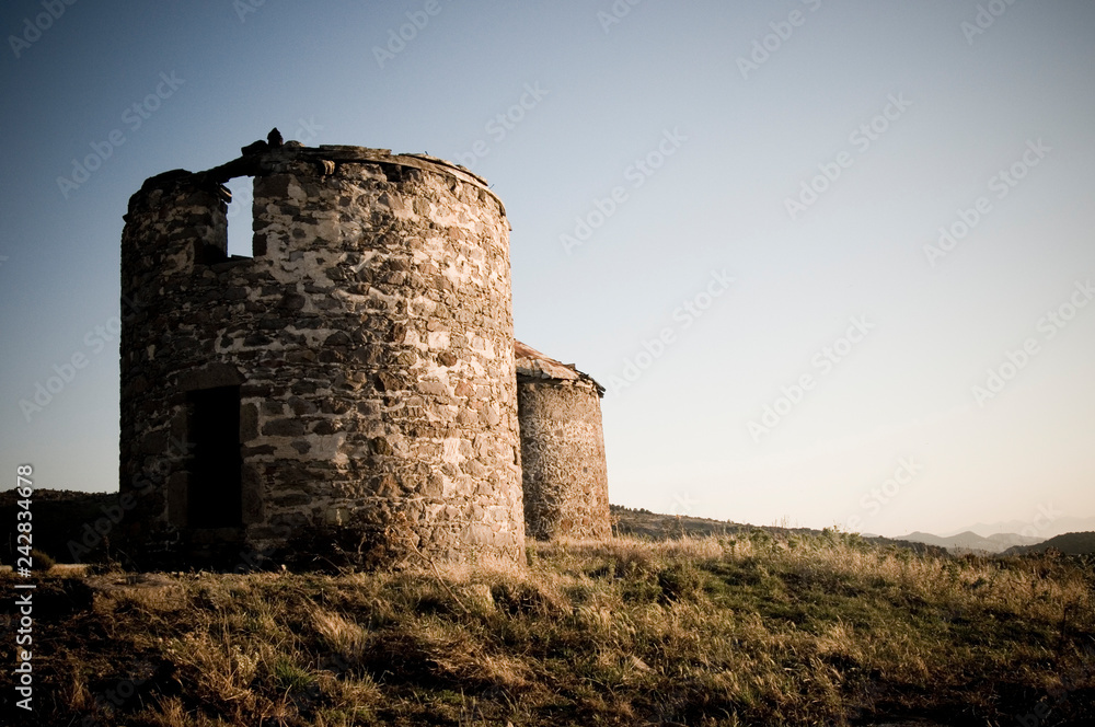 Some old ruins of ancient stone windmills on hill top in the sunset light Some old ruins of ancient stone windmills on hill top in the sunset light