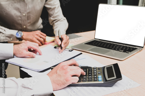 Group businessman hand using calculator Calculating bonus(Or other compensation) to employees to increase productivity.Writing paper on desk.Selective Focus