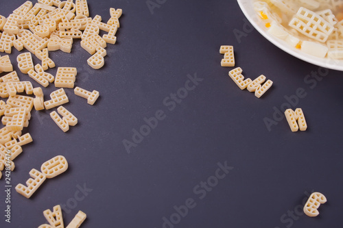 Raw macaroni and plate with soup on black background