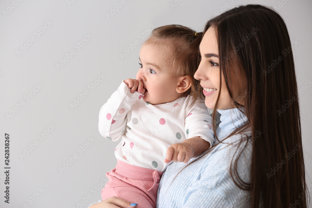 Young mother with her cute little daughter on light background Young mother with her cute little daughter on light background