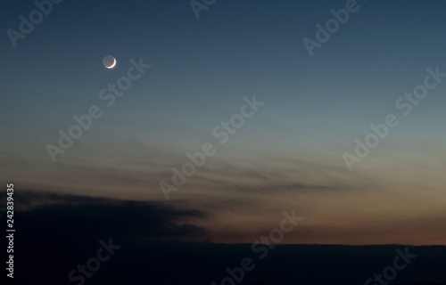 Beautiful sunset sky with crescent moon and dark clouds 