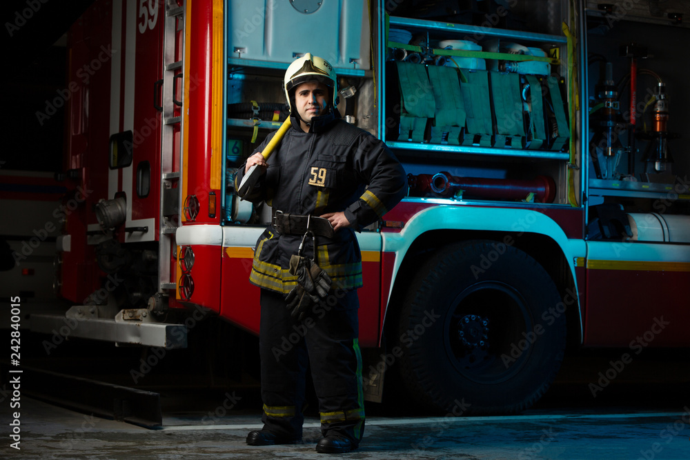 Full-length image of man firefighter with pick near fire truck at ...