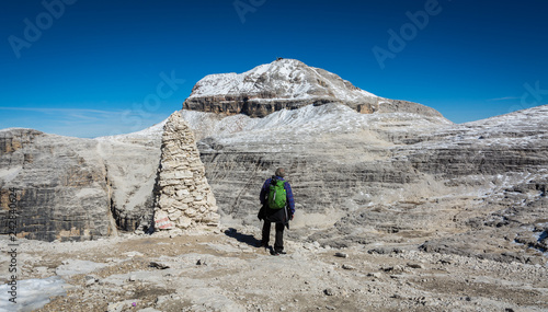 Tourist on the rock of the Sass Pordoi. View towards Piz Boe Mountain, Sella Group, Dolomites, Trentino province, Italy.