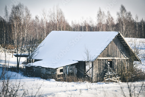 rustic weathered wood barn in the snow © Raimonds Kalva