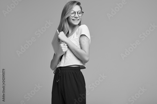 Cute teenage girl in white shirt and glasses holding digital tablet