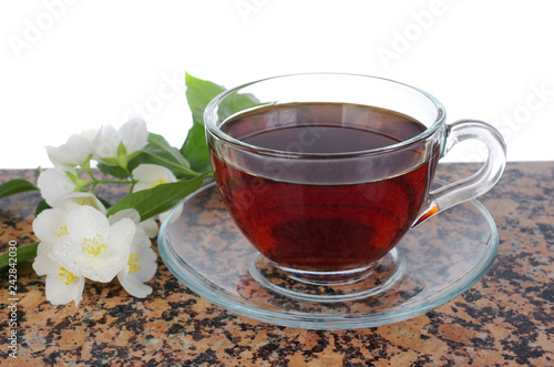 Transparent cup with tea, jasmine flowers on a white background