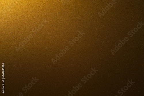 Golden shiny background illuminated by a single light source from the edge . golden paper dark gradient
