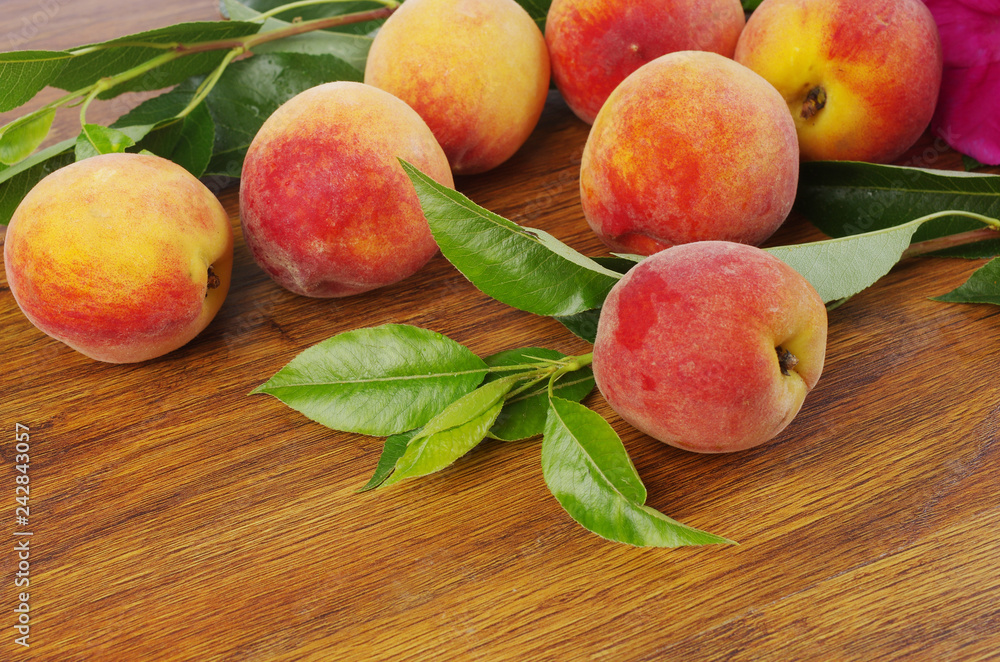 Ripe peaches and leaves on wooden table Ripe peaches and leaves on wooden table