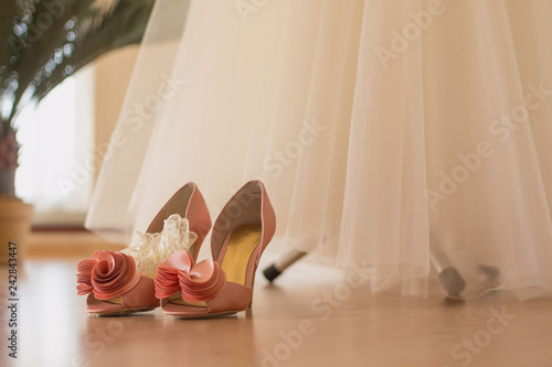 The bride's shoes stand on the floor near the wedding dress