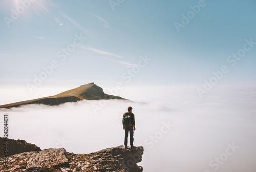Man explorer standing alone on cliff edge mountain over clouds active travel adventure lifestyle vacations outdoor in Norway photo