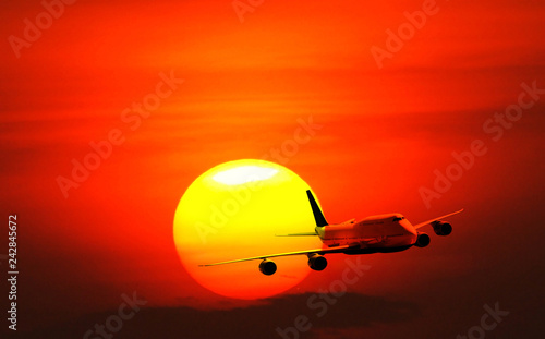 Big white airplane is flying over the sun with colorful sky at sunset for Business trip with Commercial plane , Transportation, import-export and logistics, Travel concept