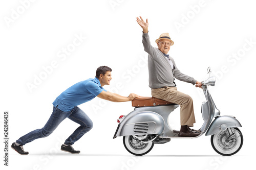 Young guy pushing a senior on a vintage scooter who is waving
