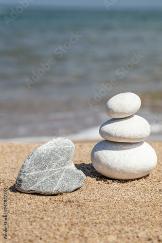 heart shaped rock and stack of pebble stones on balance on a beach