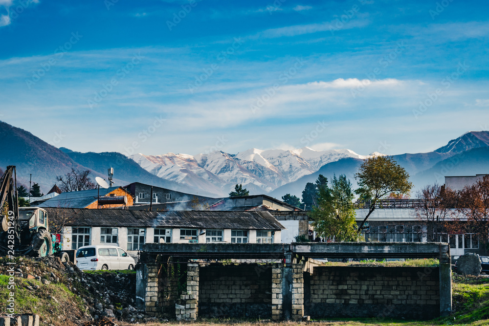 View of the snow-covered and wooded mountains in a small residential village of Azerbaijan. Destroyed buildings in the foreground.