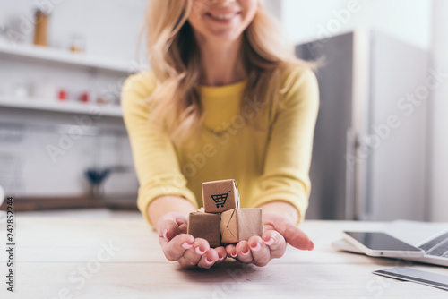 cropped view of blonde woman holding decorative packages in hands
