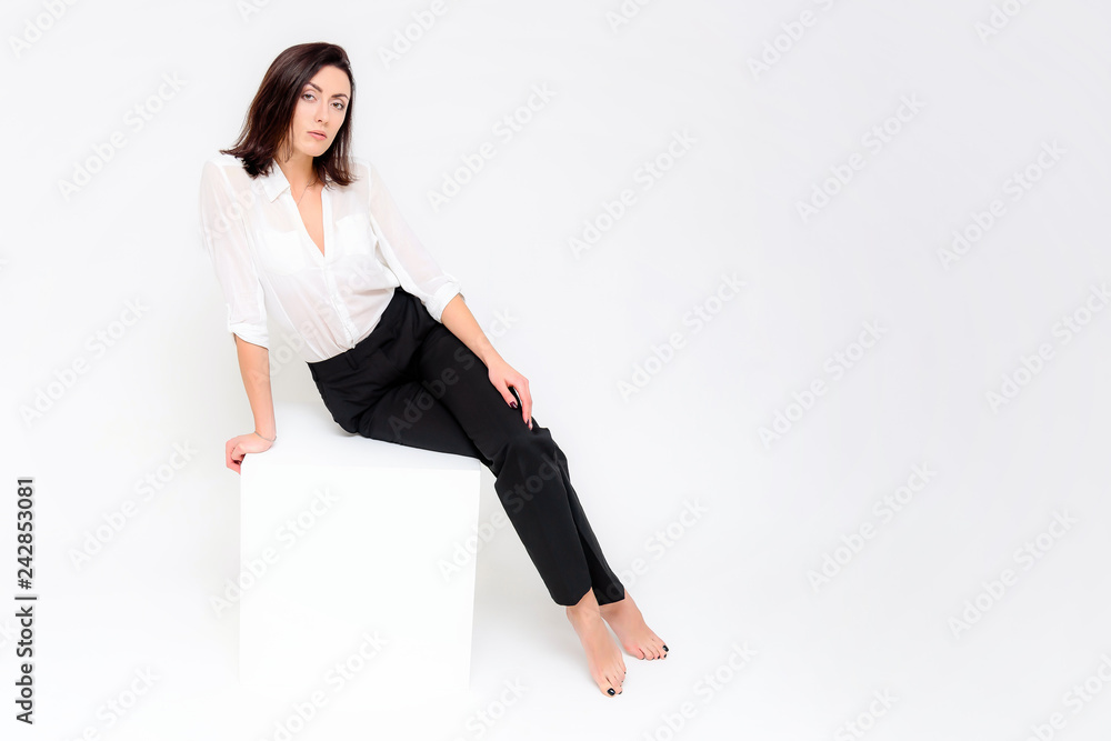 Concept portrait of a girl sitting on a white background in a business suit in different poses with different emotions. It in the middle of the frame, next to the white cubes, next is another cube. Concept portrait of a girl sitting on a white background in a business suit in different poses with different emotions. It in the middle of the frame, next to the white cubes, next is another cube.