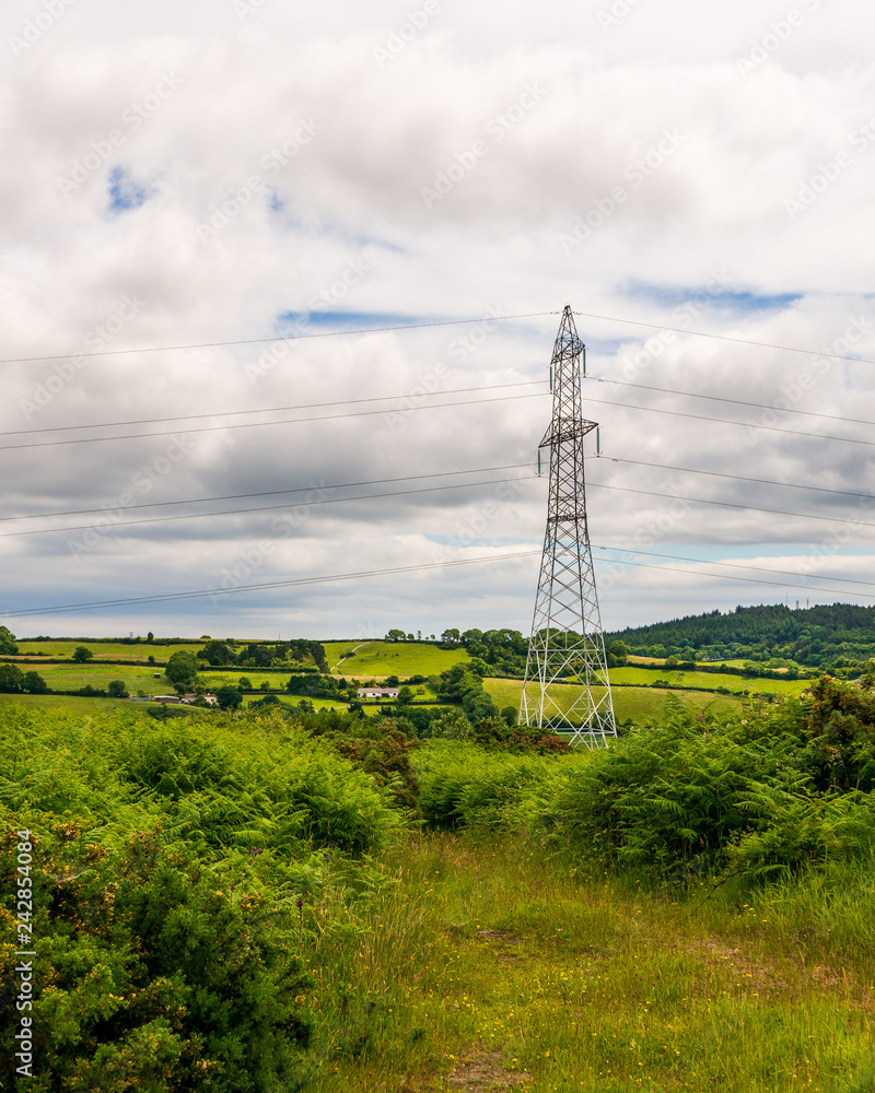 Single high voltage tower in a green hills landscape. Typical Irish countryside scene in Wicklow, Ireland.