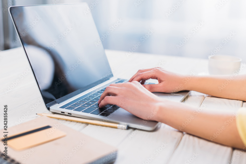 Fototapeta premium cropped view of woman typing on laptop at home