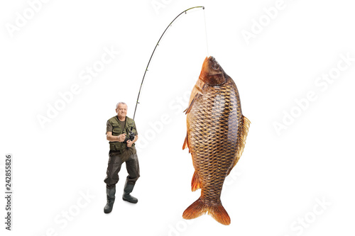 Photography Mature fisherman with a carp fish on a fishing rod