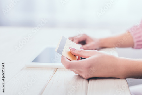 cropped ciew of woman holding credit card in hand near digital tablet