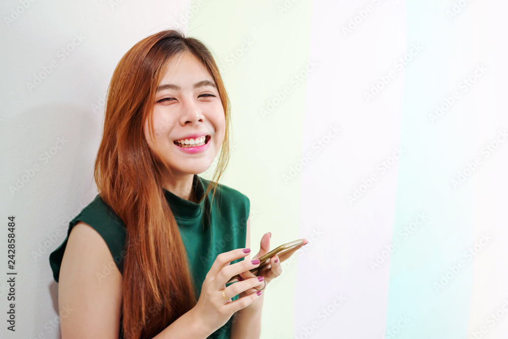 Portrait of Young Happy Woman, Looking at camera with Charming Smile while using a Smart Phone, Side view Portrait of Young Happy Woman, Looking at camera with Charming Smile while using a Smart Phone, Side view