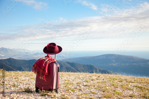 Foto Suitcase with felt burgundy hat and plaid scarf in autumn mountains