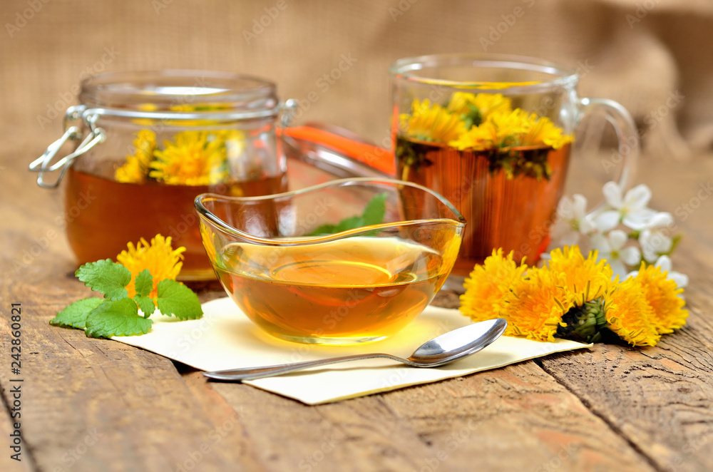 Dandelion honey, herbal tea, full jar of honey, spring flower, fresh mint leaves, spoon and dandelion head around Dandelion honey, herbal tea, full jar of honey, spring flower, fresh mint leaves, spoon and dandelion head around